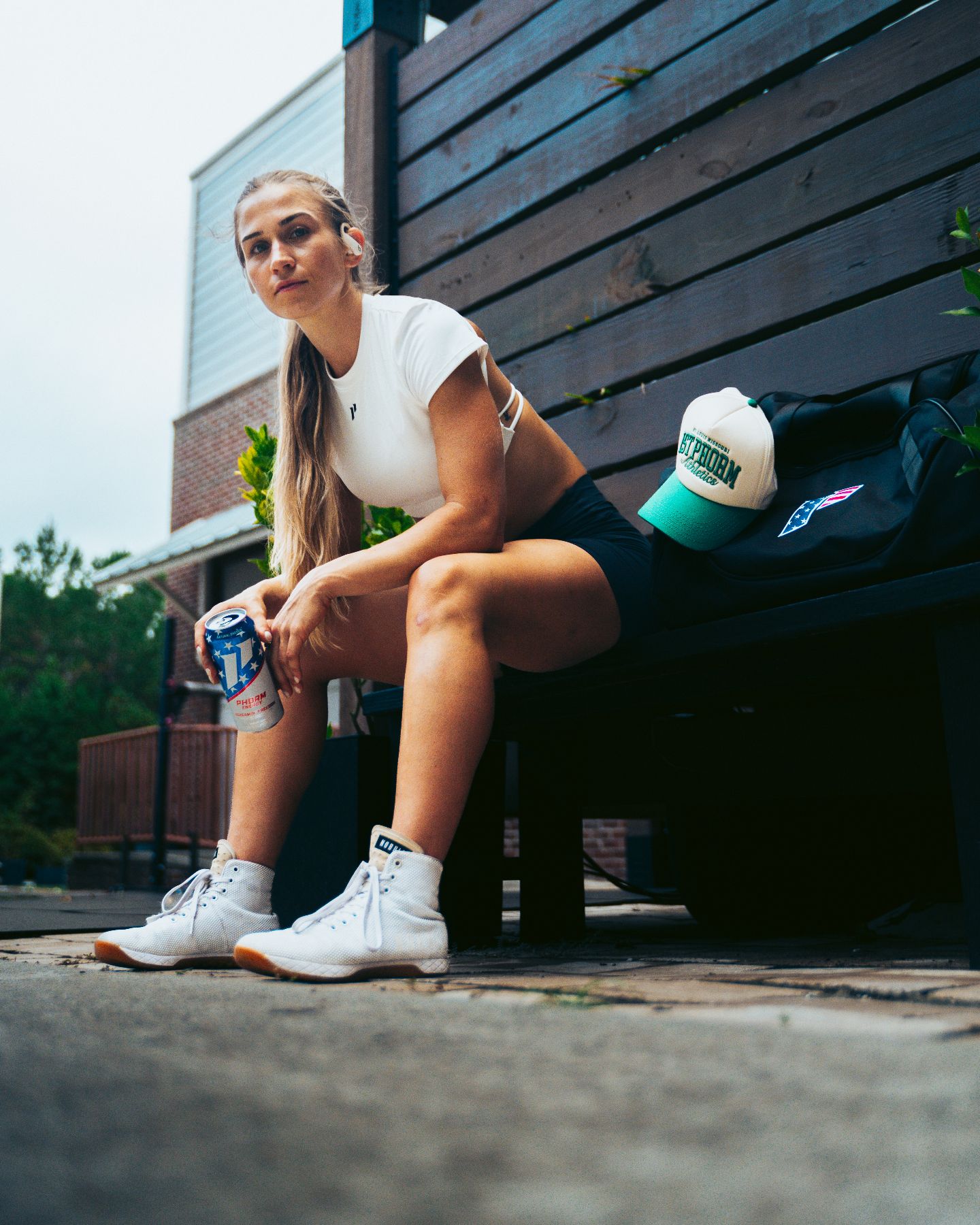 The coach sits on an outdoor bench with a drink after training.