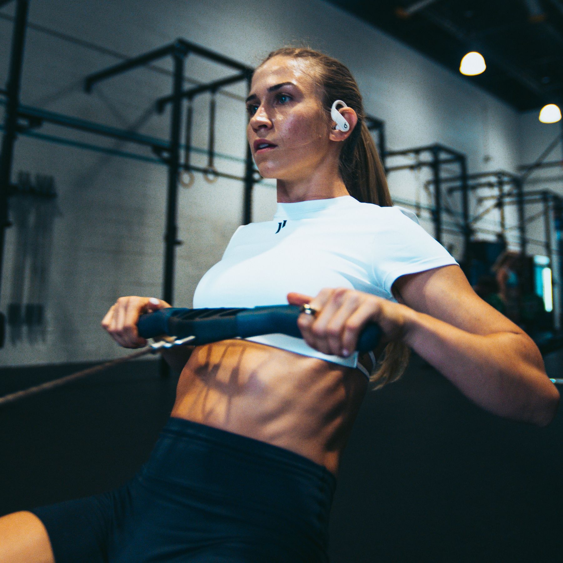 The coach pulls a cable bar towards her chest in a gym.